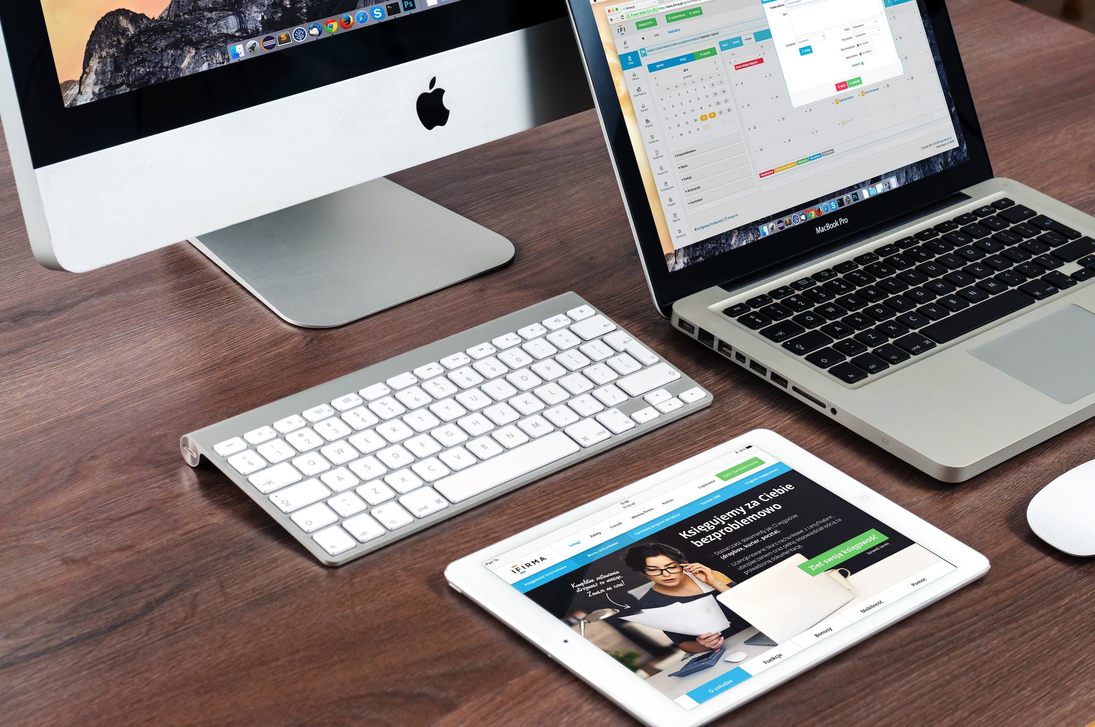 A desk with an iMac, Macbook Pro and iPad sat on it
