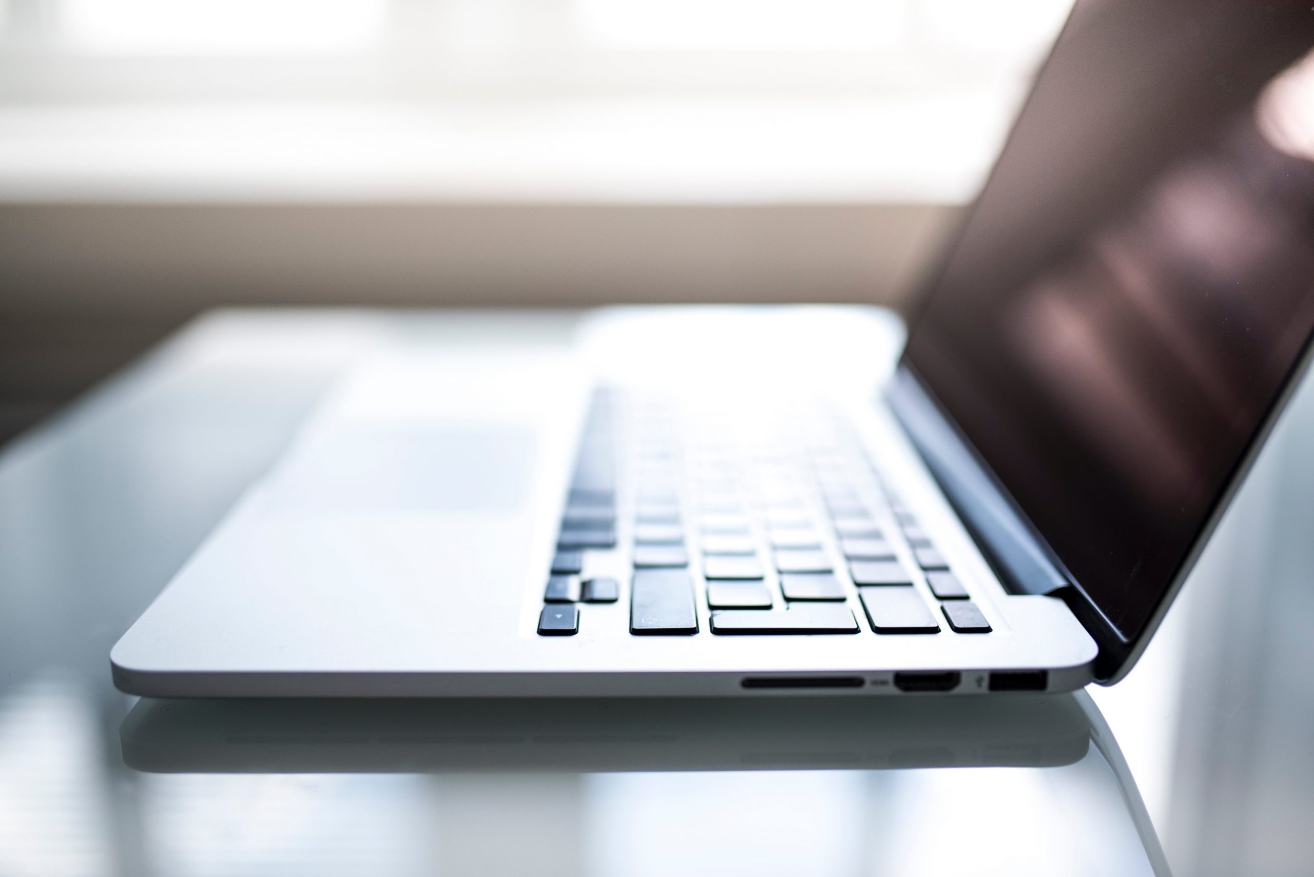 A partially blurred out laptop sat on a transparent desk