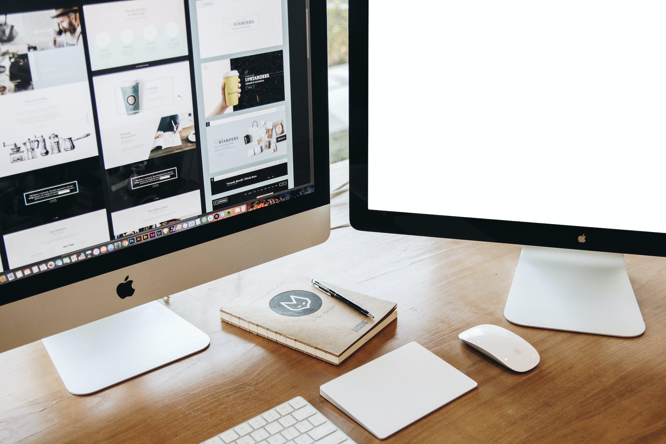 A iMac sat on a oak desk with a keyboard, trackpad and mouse