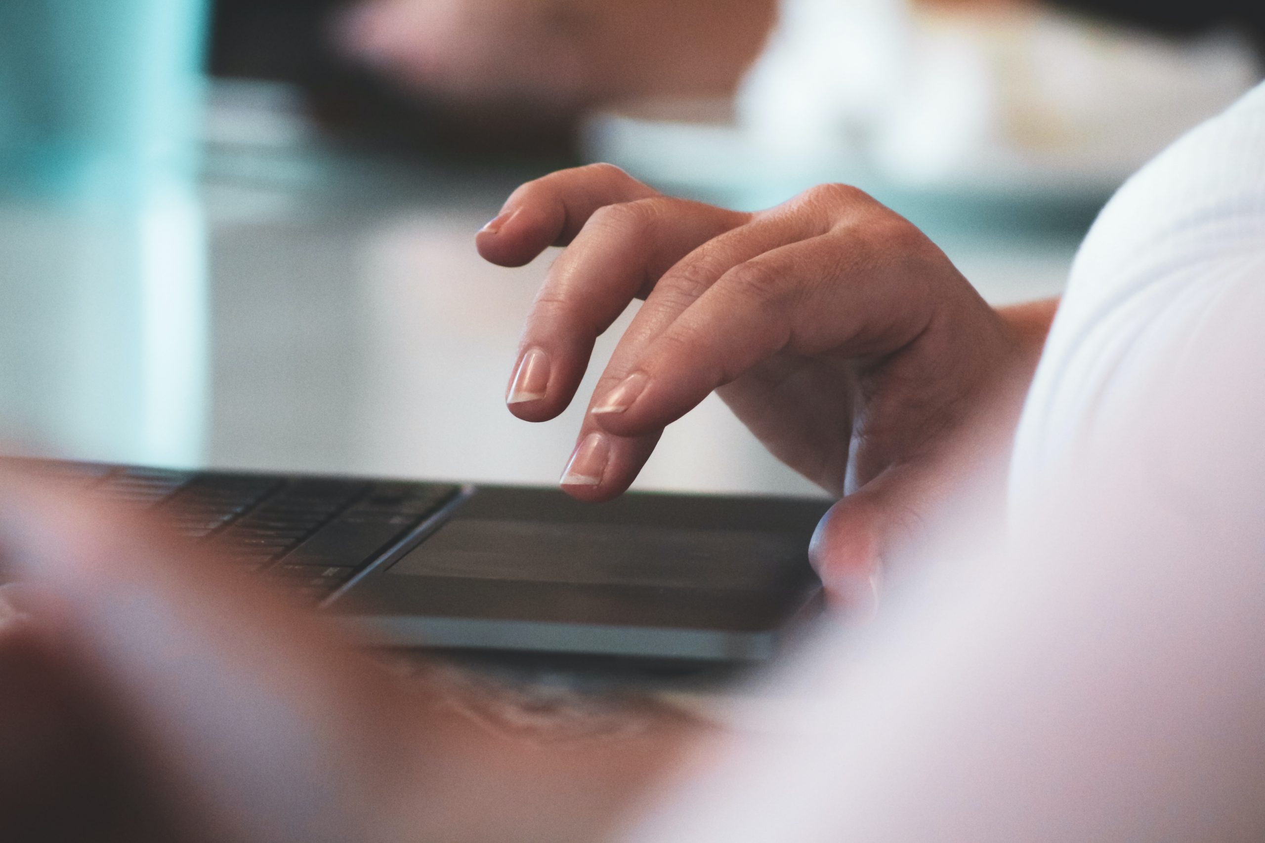 A set of fingers hovering over a laptop trackpad